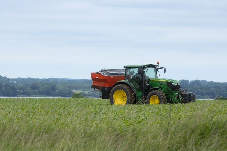 green tractor pulling red wagon in a field of green crops