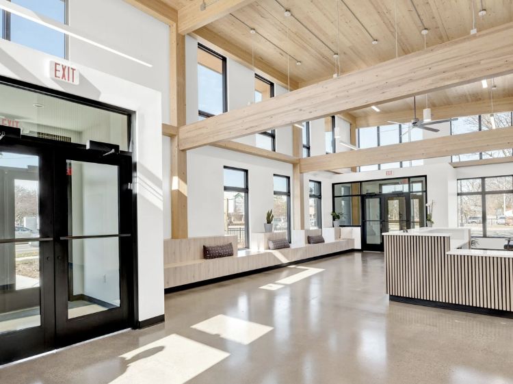 Front lobby of a building with a lot of windows and natural lighting.