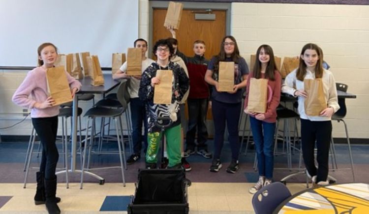 A group of youth holding up paper sacks.