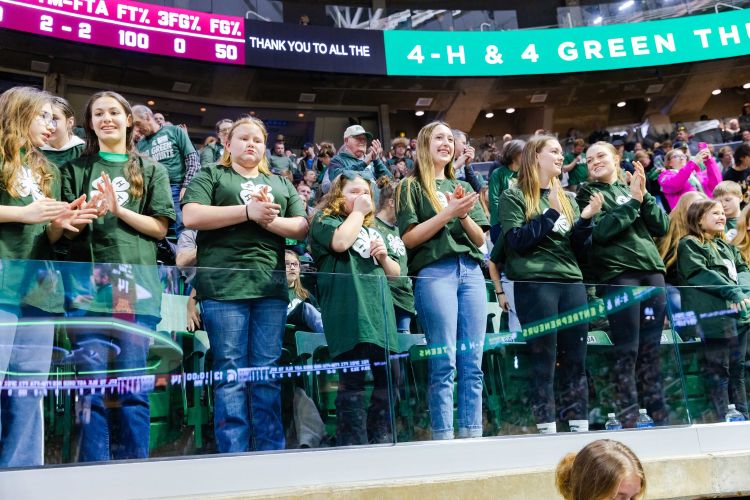A group of 4-H youth with 4-H shirts on with 4-H on the banner behind them.