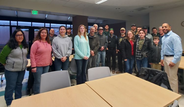 A group of people in a classroom stand and pose for a picture.