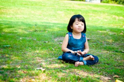 Small child sitting on the grass with eyes closed