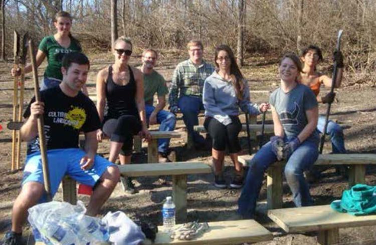 Photo of landscape architecture students taking a break while volunteering at Woldumar Nature Center.