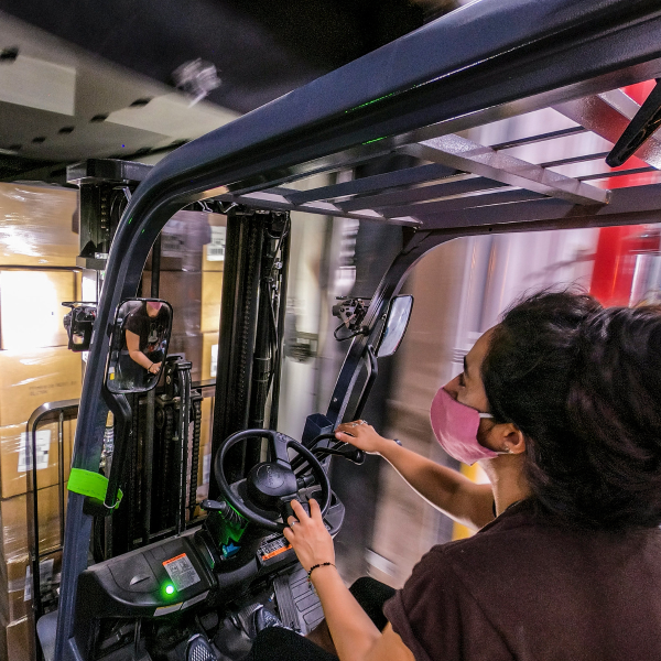 Worker moves a pallet of food boxes using a fork lift.