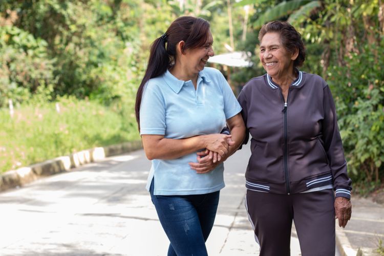 Two older women walking outside and smiling.