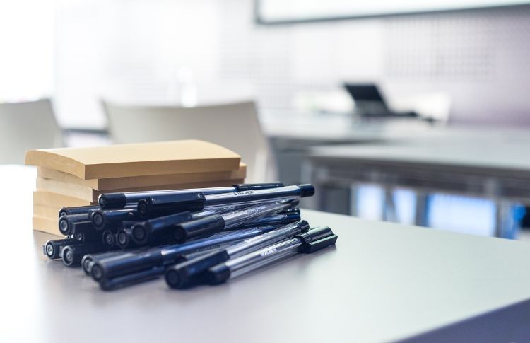 Pens and notepads stacked up on a table.