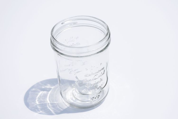 A photo of an empty glass canning jar without a lid.