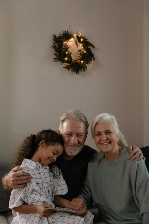 Two elderly people posing for a photo with a young child.