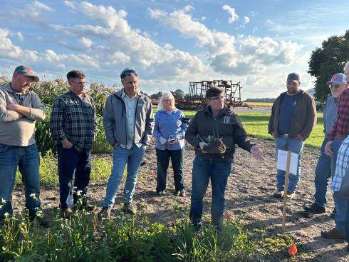Participants at the 2025 Cover Crop Workshop discuss below ground biomass while a speaker holds a soil sample during the presentation.