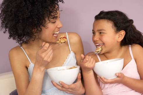 A mother and daughter eating a bowl of cereal