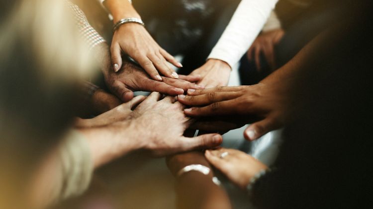 Various people putting their hands in a circle.