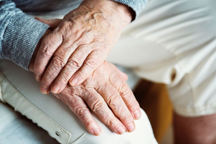 Wrinkly hands folded over each other.