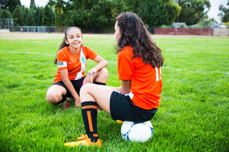 Girls sitting on soccer field with ball
