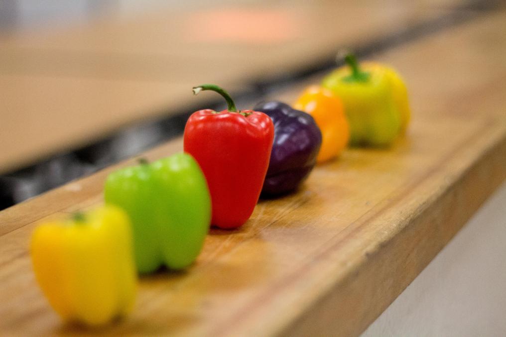 Red, green, yellow, and purple bell peppers lined up