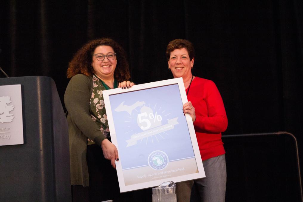 Two women stand with a large poster