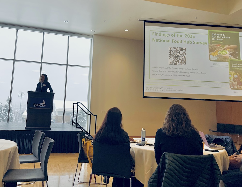 Jude Barry stands at podium and presents to the summit attendees