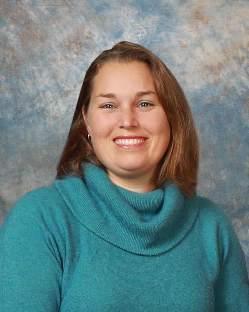Studio portrait of Cara Robison wearing a teal sweater, facing the camera against a mottled blue and gray background.